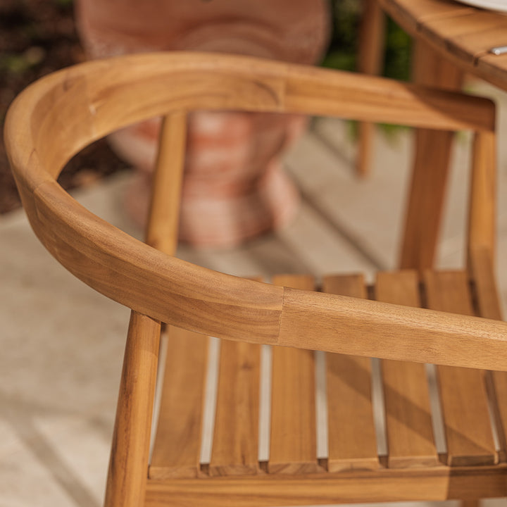 Close-up of a wooden chair with blurred feet in the background