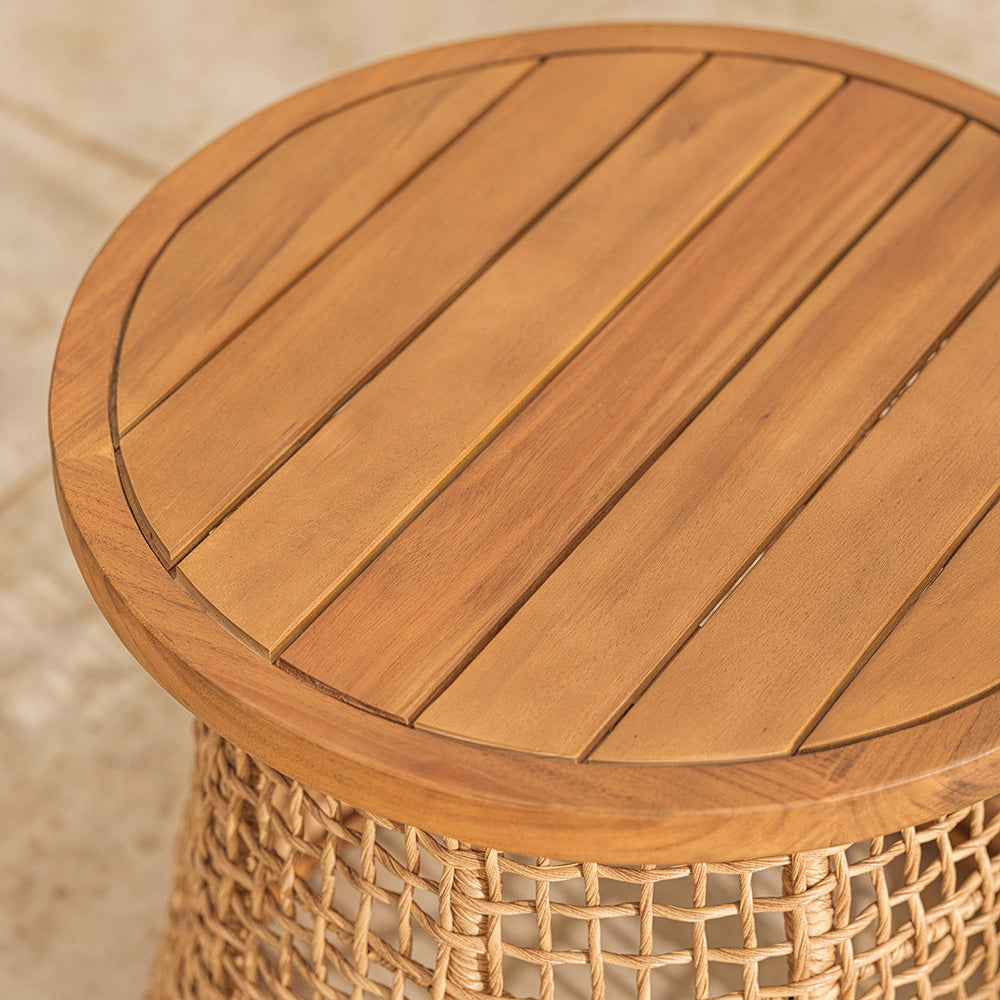 Wooden round table with wicker base on a neutral patio