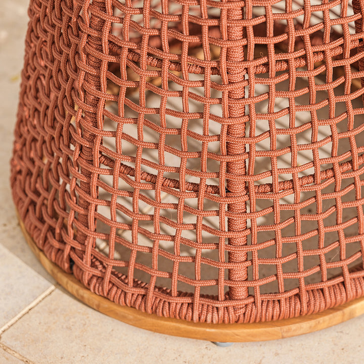 Close-up of a woven red garden table stand on a neutral patio