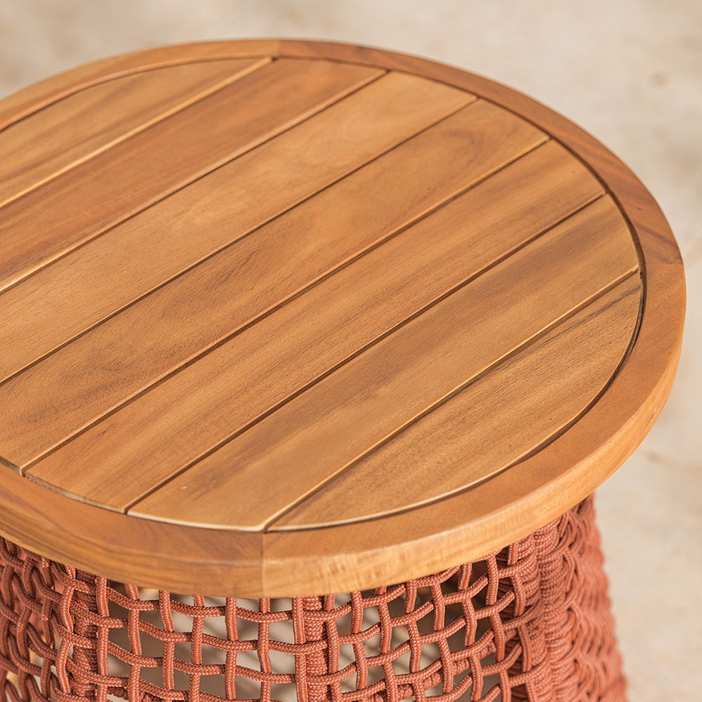Wooden garden table top with a red woven base on a neutral patio