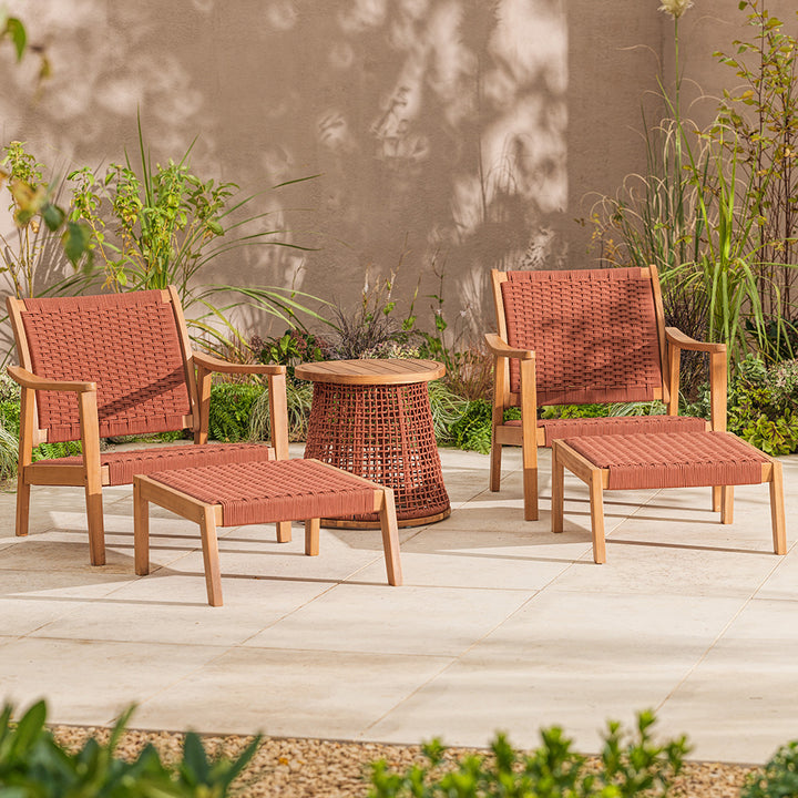 Outdoor patio set with red wicker and acacia wood chairs, footstools and table on a patio