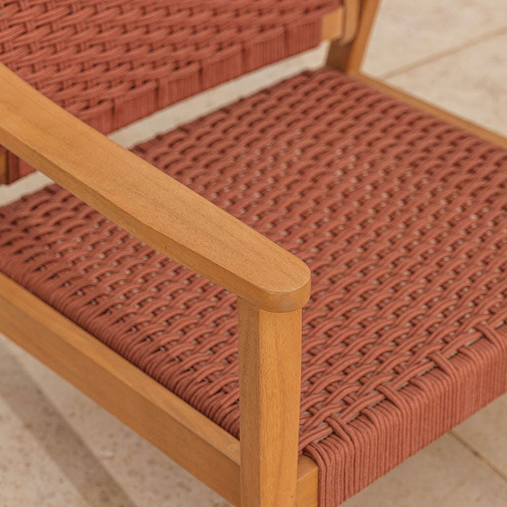 Close-up of a red wicker chair with wooden armrests on a tiled floor.
