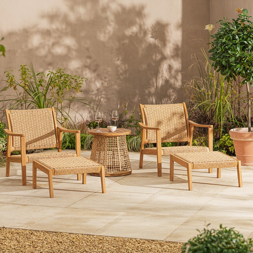 Outdoor patio set with wicker chairs and table on a stone patio.