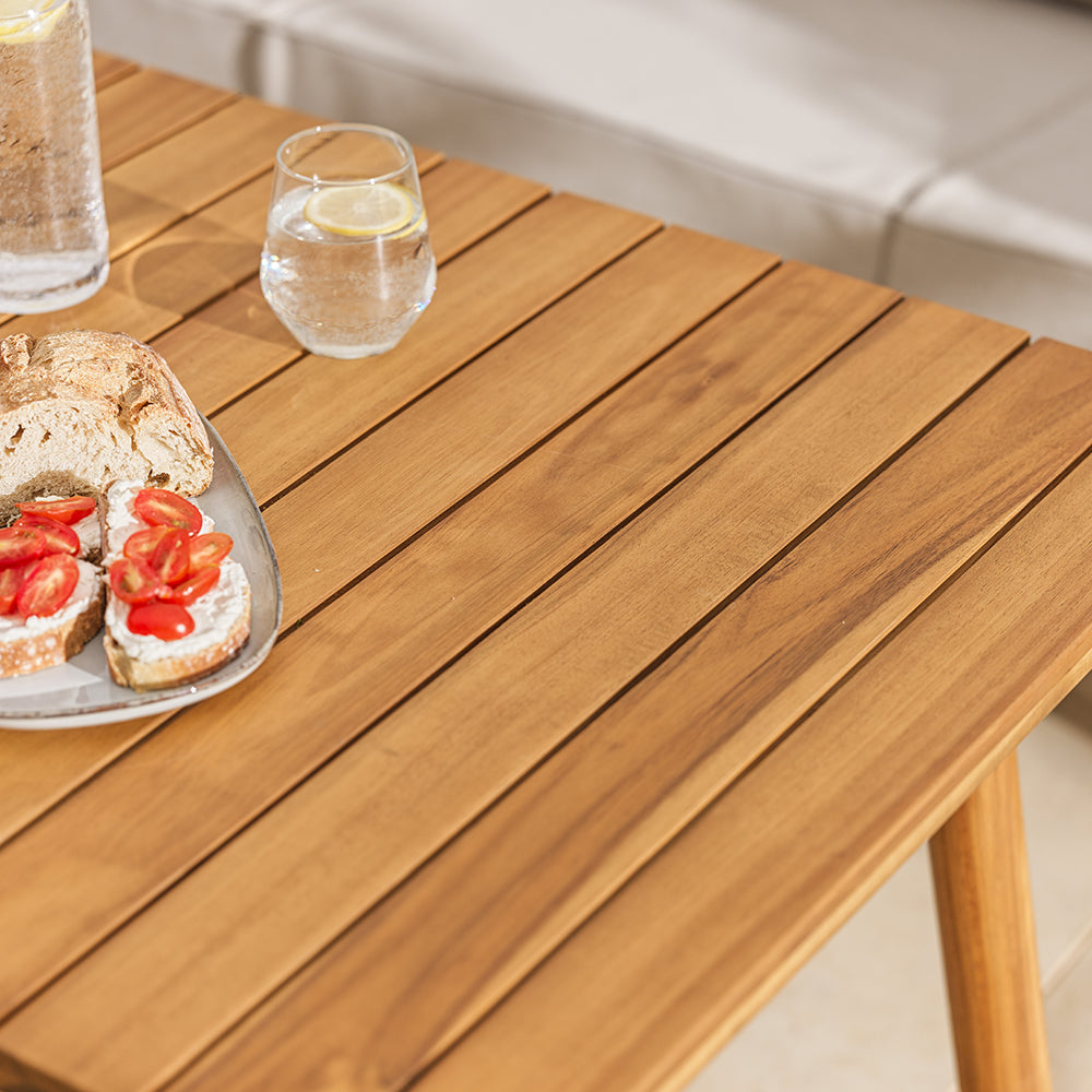 Wooden table with a plate of sandwiches and glasses of water on a patio setting