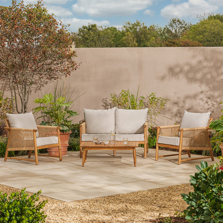 Outdoor patio set with wooden chairs and sofa against a beige wall.