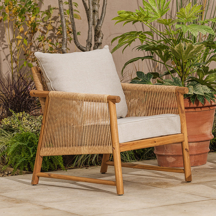 Wicker and wooden chair with beige cushion in a garden setting