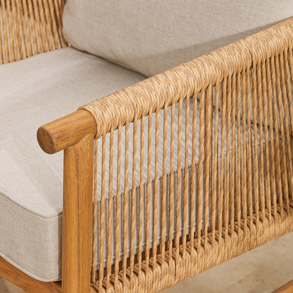 Close-up of a wicker chair with wooden armrests and beige cushions.