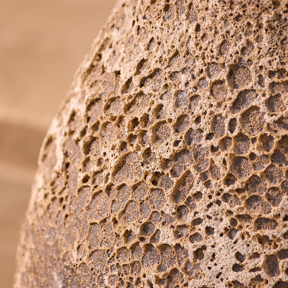 Close-up of a textured stone planter surface with a blurred garden background