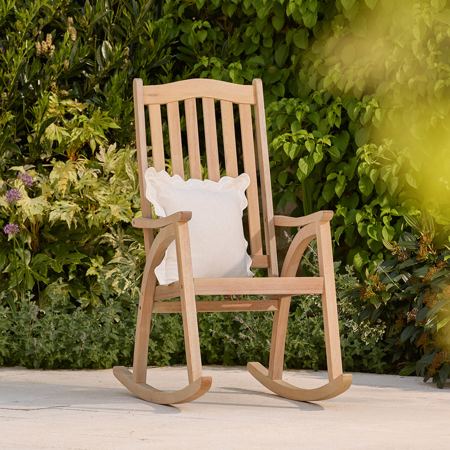 Wooden rocking chair with a white pillow in a garden setting