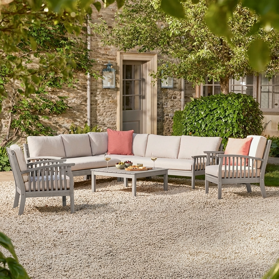 Outdoor patio set with a corner sofa and two wooden armchairs chairs on a stone patio.