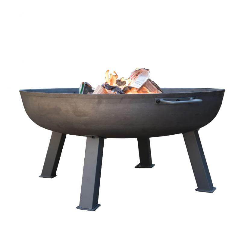 Hoole Cast Iron Fire Pit Bowl with sturdy steel legs and side handles, displayed with firewood. A durable, handcrafted outdoor fire pit available in multiple sizes.